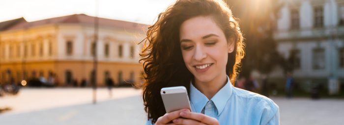 Portrait of a beautiful smiling woman using a mobile phone outdoors